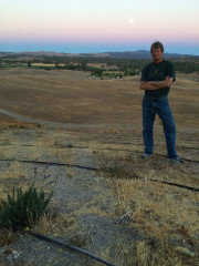 The farmer standing next to irrigation lines at sunset at Al Pie Del Cielo Olive Farm and Vineyard in San Luis Obispo, California.